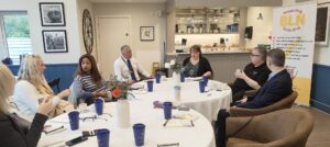 A group of people sitting round a table networking, drinking and talking